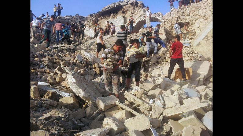 People pick through the rubble of the destroyed Mosque of the Prophet Yunus, or Jonah, in Mosul. The destruction of the tomb by ISIS this week epitomizes the plight of Christians in Iraq.
