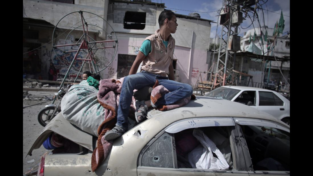 During a 12-hour cease-fire in Gaza City's Shijaiyah neighborhood on Saturday, July 26, a Palestinian man sits atop a car filled with belongings that were salvaged from a destroyed home.