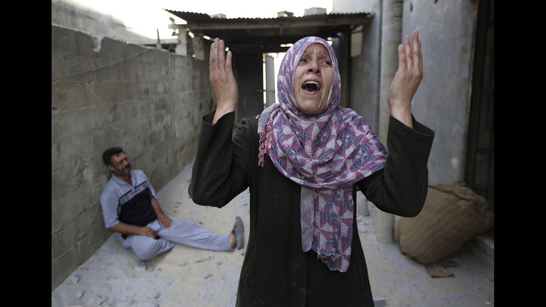 As her brother-in-law Mazen Keferna weeps on the ground, Manal Keferna cries upon discovering her family home destroyed by airstrikes in Beit Hanoun on July 26.