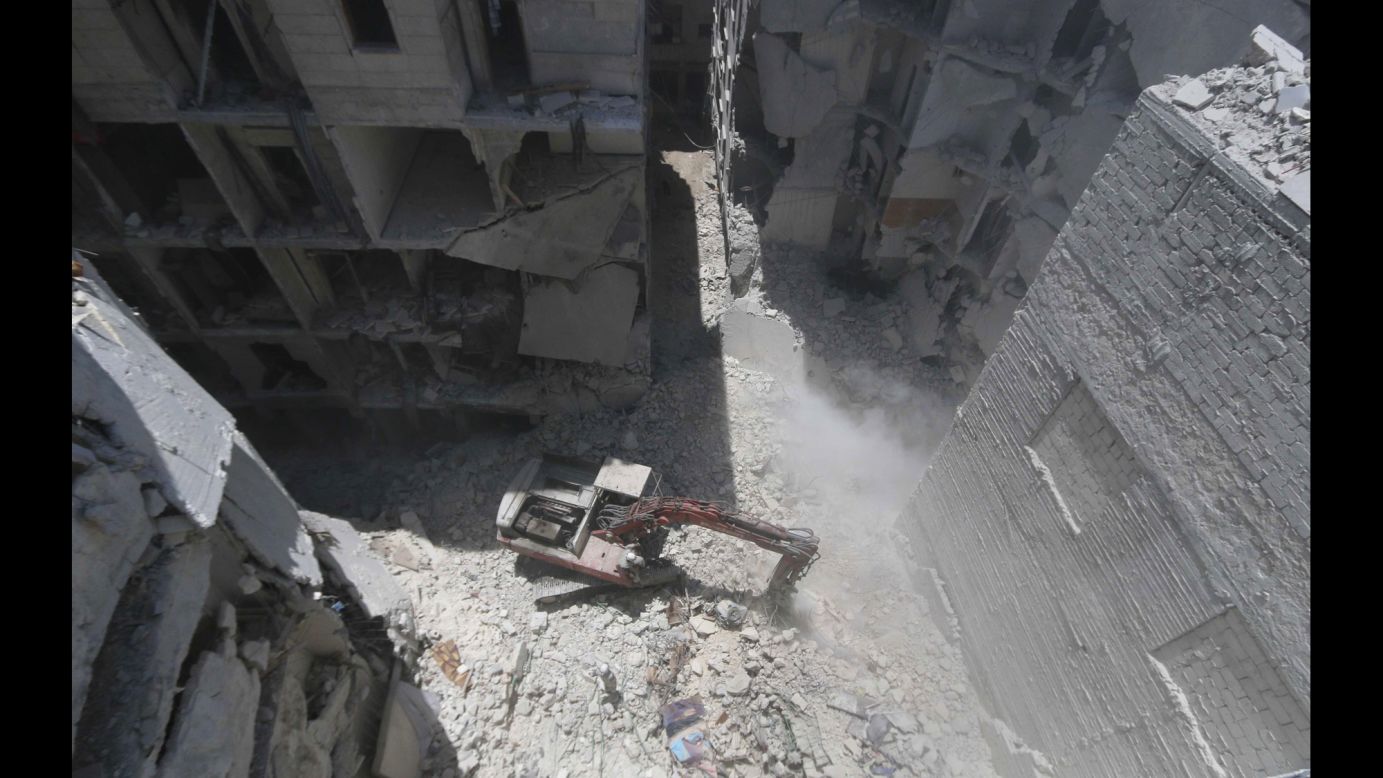 A man clears debris at the site of an alleged barrel-bomb attack in Aleppo on Tuesday, July 15.