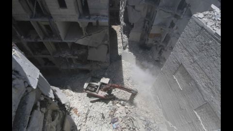 A man clears debris at the site of an alleged barrel-bomb attack in Aleppo on Tuesday, July 15.