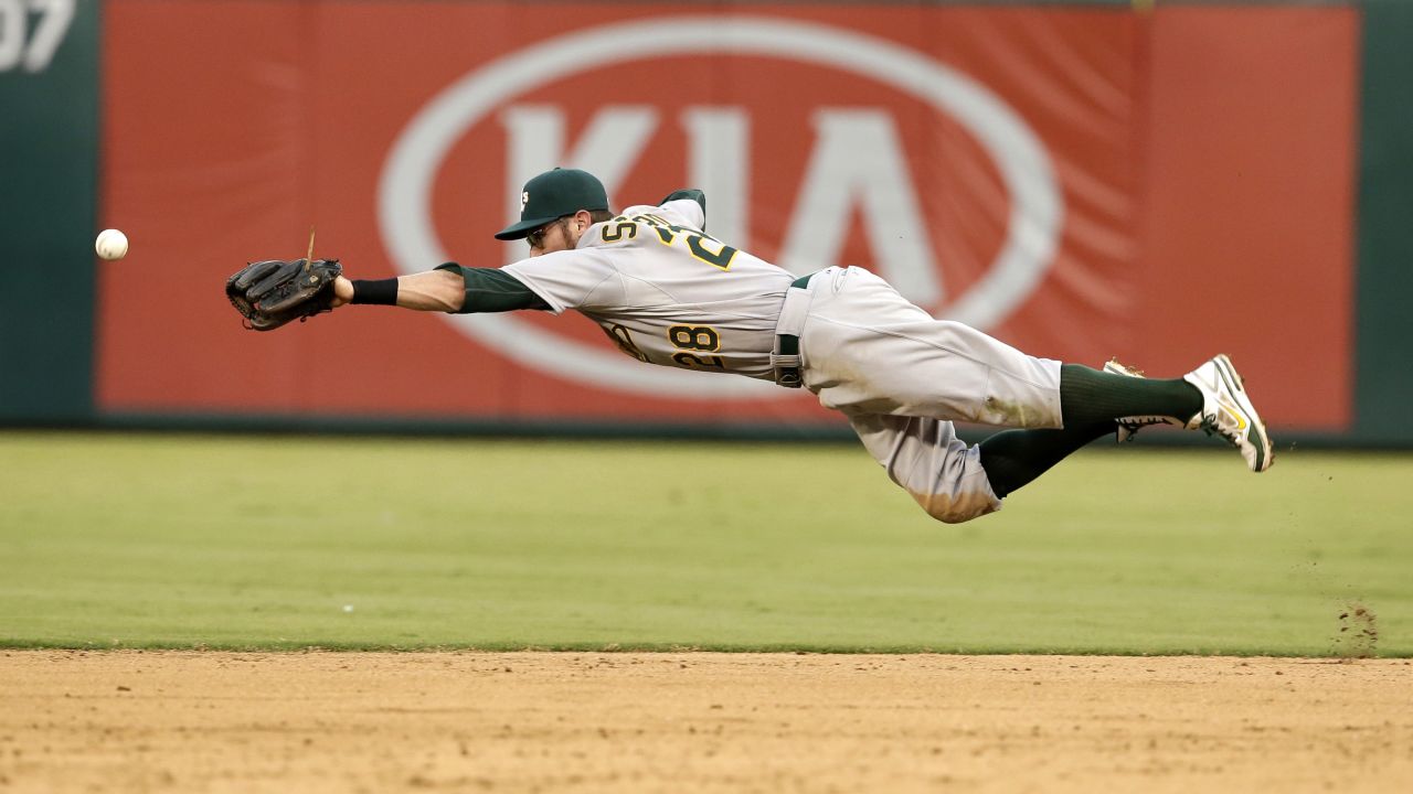 Oakland Athletics second baseman Eric Sogard stretches out as he tries to grab a ball hit by Texas' Alex Rios in the fifth inning of a Major League Baseball game Sunday, July 27, in Arlington, Texas.