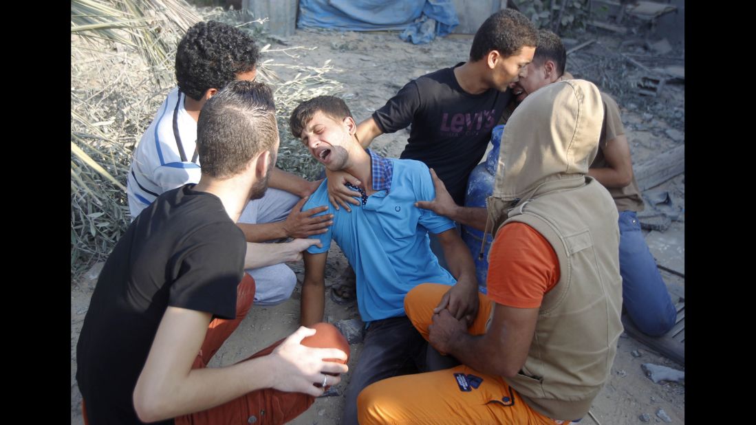 Near the rubble of their home in Rafah, Palestinian men mourn July 29 for people killed during an airstrike.