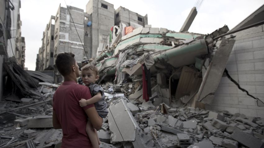 A Palestinian man carrying a child looks at the destroyed house of Ismail Haniya, Hamas' leader in Gaza, after it was hit by an overnight Israeli air strike, on July 29, 2014 in Gaza City.
