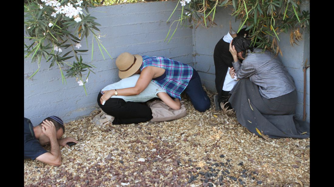 Israelis take cover from a Palestinian rocket attack from Gaza during the funeral of Israeli soldier Meidan Maymon Biton, which was held at a cemetery in Netivot, Israel, on Tuesday, July 29.