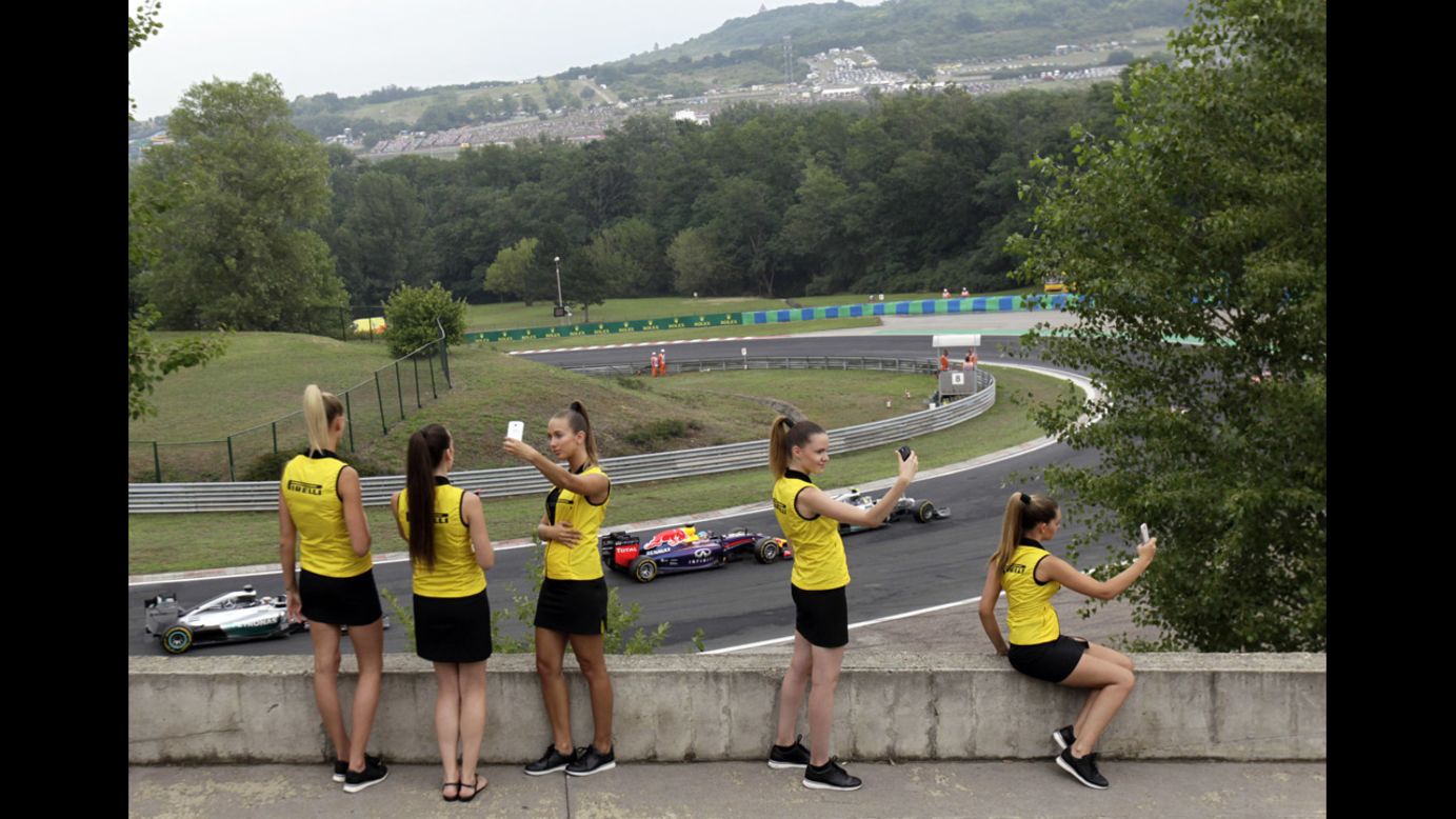 Hostesses with the Italian tire company Pirelli take selfies Sunday, July 27, as Formula One drivers compete in the Hungarian Grand Prix near Budapest, Hungary.