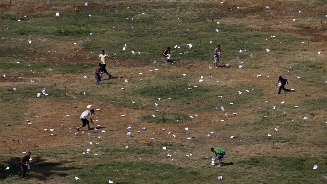 Palestinians gather leaflets that fell from an Israeli plane on July 30. The leaflets warned residents of airstrikes in Gaza City.