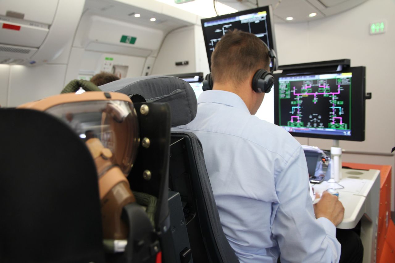 Two engineers man the test station set up in the rear cabin of the plane.