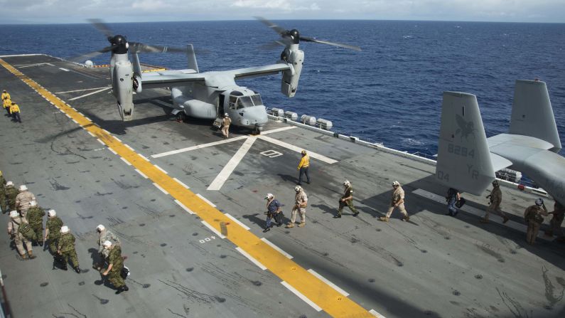 People walk past a U.S. Marine Corps Osprey aircraft aboard the amphibious assault ship USS Peleliu on July 14.