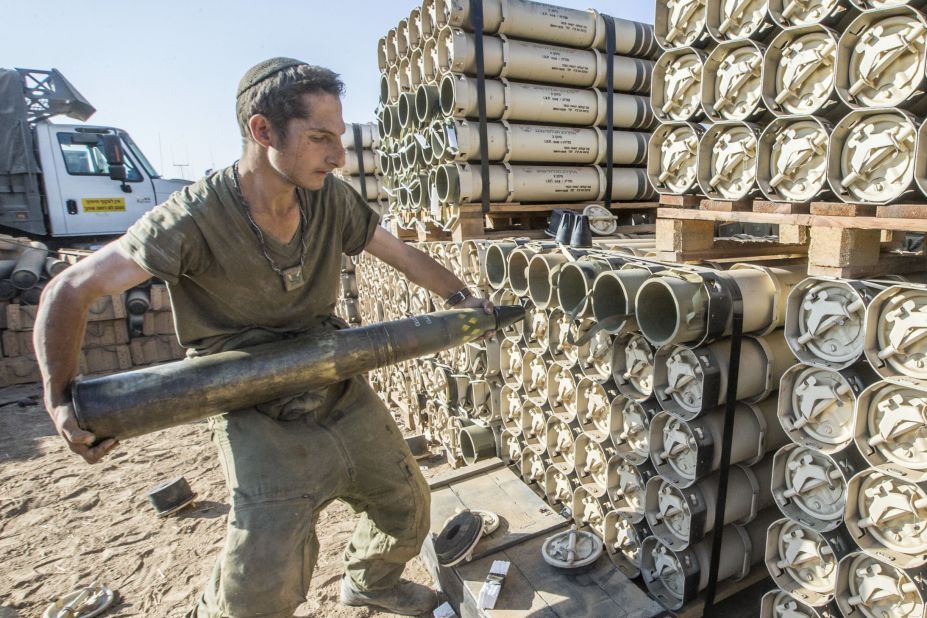 An Israeli soldier carries a shell as he prepares a tank along the Israel-Gaza border on Thursday, July 31. Israel called up 16,000 additional reservists, bolstering forces for its fight against Hamas, the militant group that controls Gaza. 