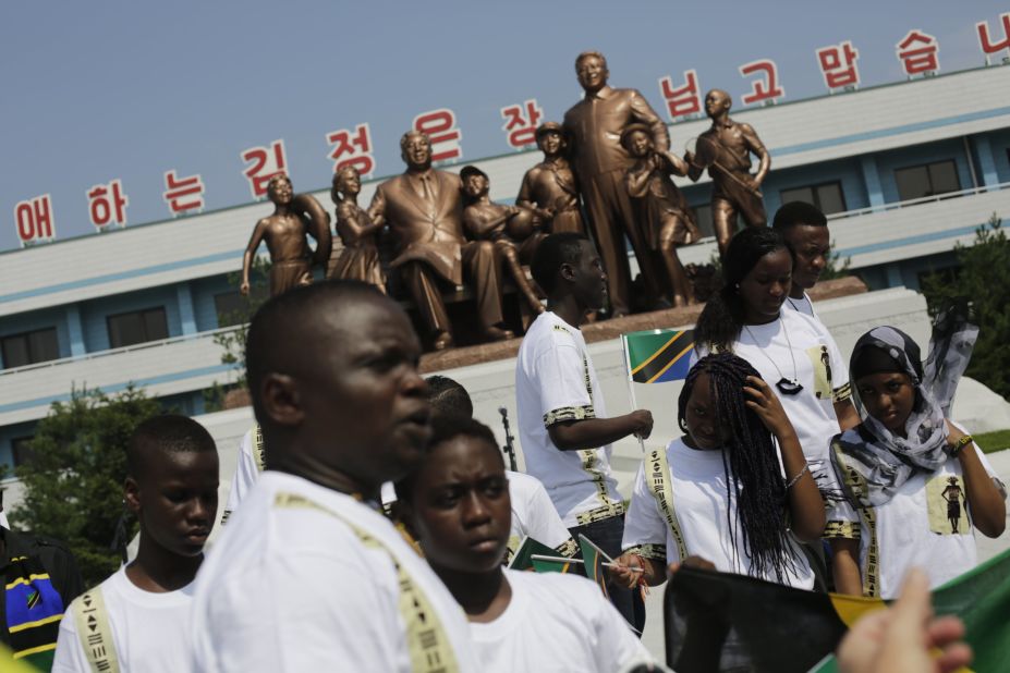 Students from the Laureat International School in Tanzania walk past a statue of the late North Korean leaders Kim Il Sung and Kim Jong Il.