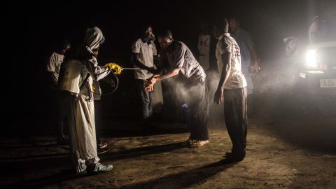 Red Cross volunteers disinfect each other with chlorine after removing the body of an Ebola victim from a house in Pendembu on July 18, 2014.