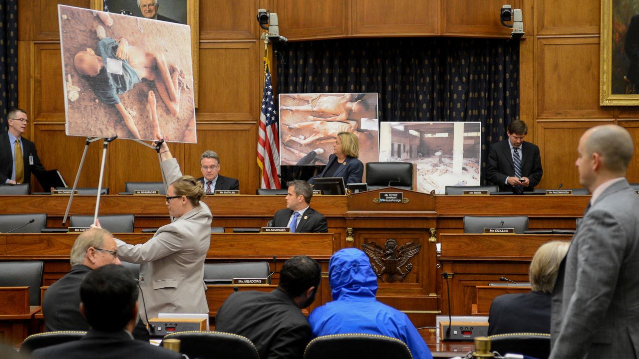 Image #: 31125448    Photographs of victims of the Assad regime are displayed as a Syrian Army defector known as "Caesar", center, appears in disguise to speak before the House Foreign Affairs Committee at a briefing called "Assad's Killing Machine Exposed: Implications for U.S. Policy" concerning the Assad regime, on Capitol Hill, Washington, D.C., Thursday, July 31, 2014. "Caesar" was apparently a witness to Bashar al-Assad's brutality and as smuggled more than 50,000 photographs depicting the torture and execution of more then 10,000 dissidents. ()     The Washington Times /Landov
