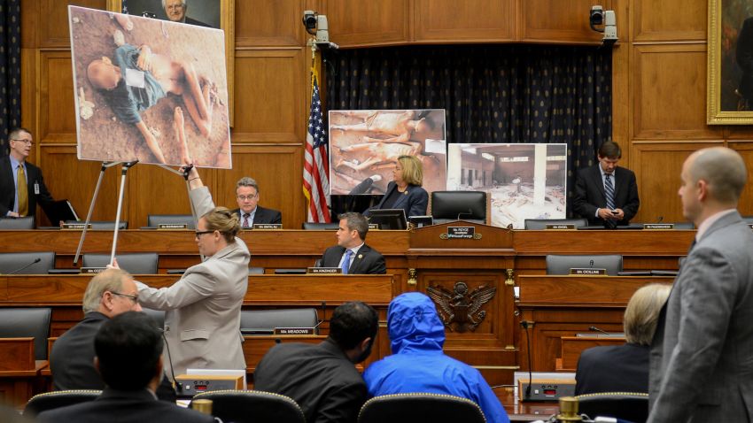 Image #: 31125448    Photographs of victims of the Assad regime are displayed as a Syrian Army defector known as "Caesar", center, appears in disguise to speak before the House Foreign Affairs Committee at a briefing called "Assad's Killing Machine Exposed: Implications for U.S. Policy" concerning the Assad regime, on Capitol Hill, Washington, D.C., Thursday, July 31, 2014. "Caesar" was apparently a witness to Bashar al-Assad's brutality and as smuggled more than 50,000 photographs depicting the torture and execution of more then 10,000 dissidents. ()     The Washington Times /Landov