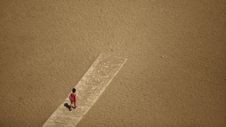 A child walks toward the shore of the Mediterranean Sea at Malagueta Beach in Malaga, Spain, on Sunday, July 27.