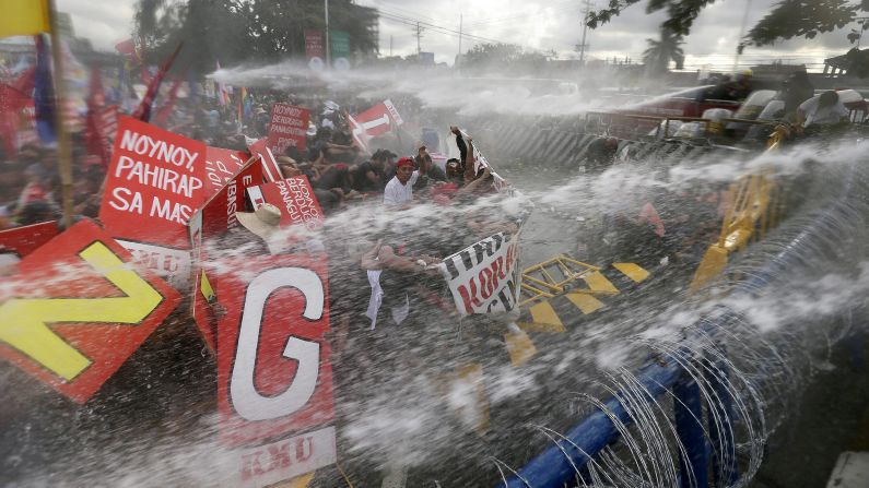 Anti-riot police officers use water cannons to disperse protesters attempting to reach the Philippine Congress in Quezon City, Philippines, on Monday, July 28, during the state of the nation address by President Benigno Aquino.