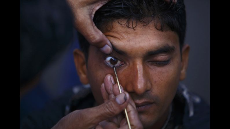 A Muslim man has kohl applied to his eyelid at a mosque as he arrives for <a href="http://religion.blogs.cnn.com/2014/06/28/the-belief-blog-guide-to-ramadan/">Eid al-Ftir</a> mass prayers, in Kathmandu, Nepal, on Tuesday, July 29.