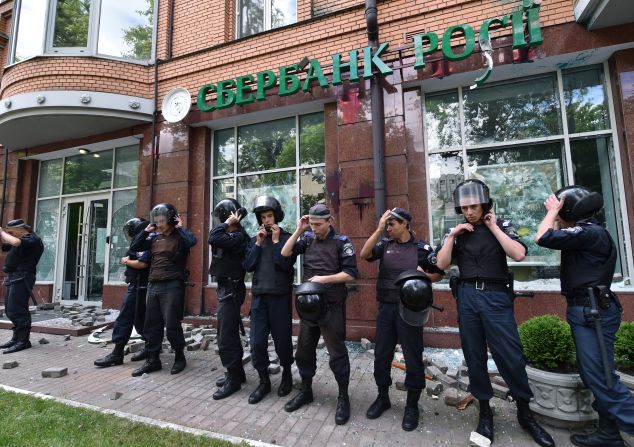 Sberbank is Russia's biggest lender and the 186th largest company globally. It reported $54.8 billion in revenues last year and $11 billion in net profit, according to its Fortune Global 500 ranking. Pictured here are policemen guarding a branch of Sberbank in Kiev.