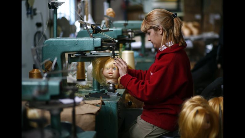 An employee sews a doll's hair to its head inside the toy factory in Buenos Aires on Monday, July 28. 