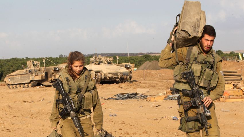 Israeli soldiers walk out from their armoured personnel carriers on August 3, along the border between Israel and Gaza after they pulled out from Gaza.