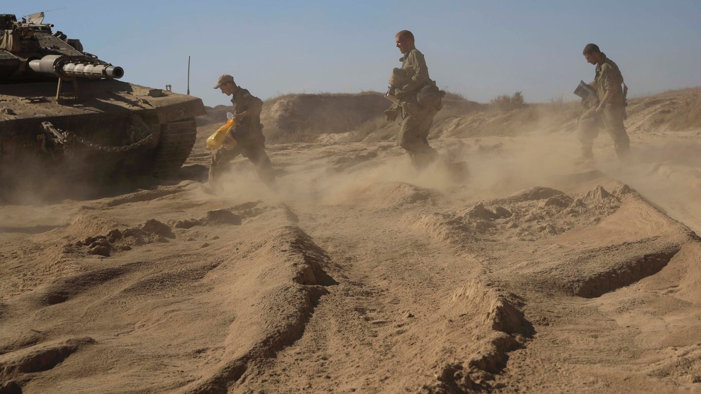 Israeli soldiers walk to their tank at a staging area near the border with Gaza on August 2.