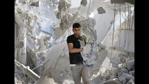A young Palestinian carries damaged copies of the Quran from the rubble of the Imam Al Shafaey mosque in Gaza City on August 2.
