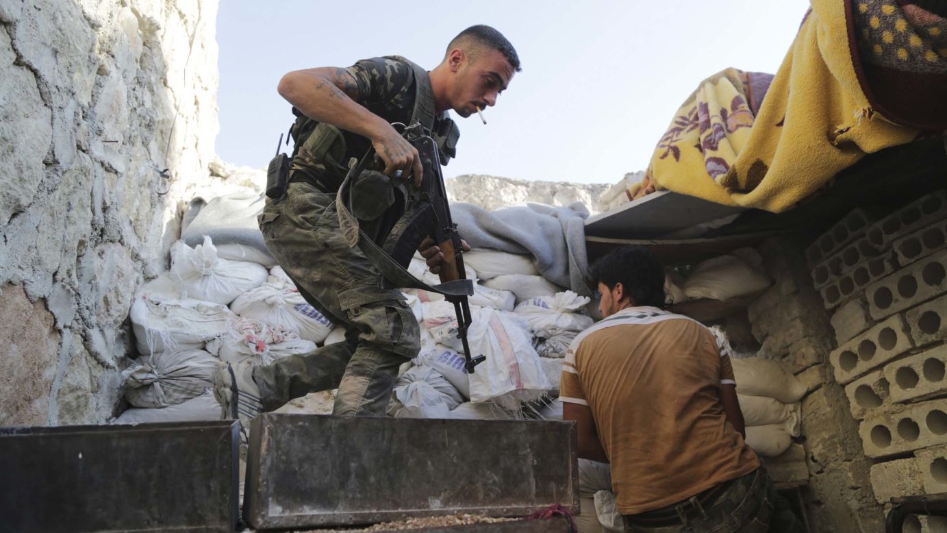 Syrian rebel fighters take up positions behind sandbags in Aleppo on Wednesday, July 30. 