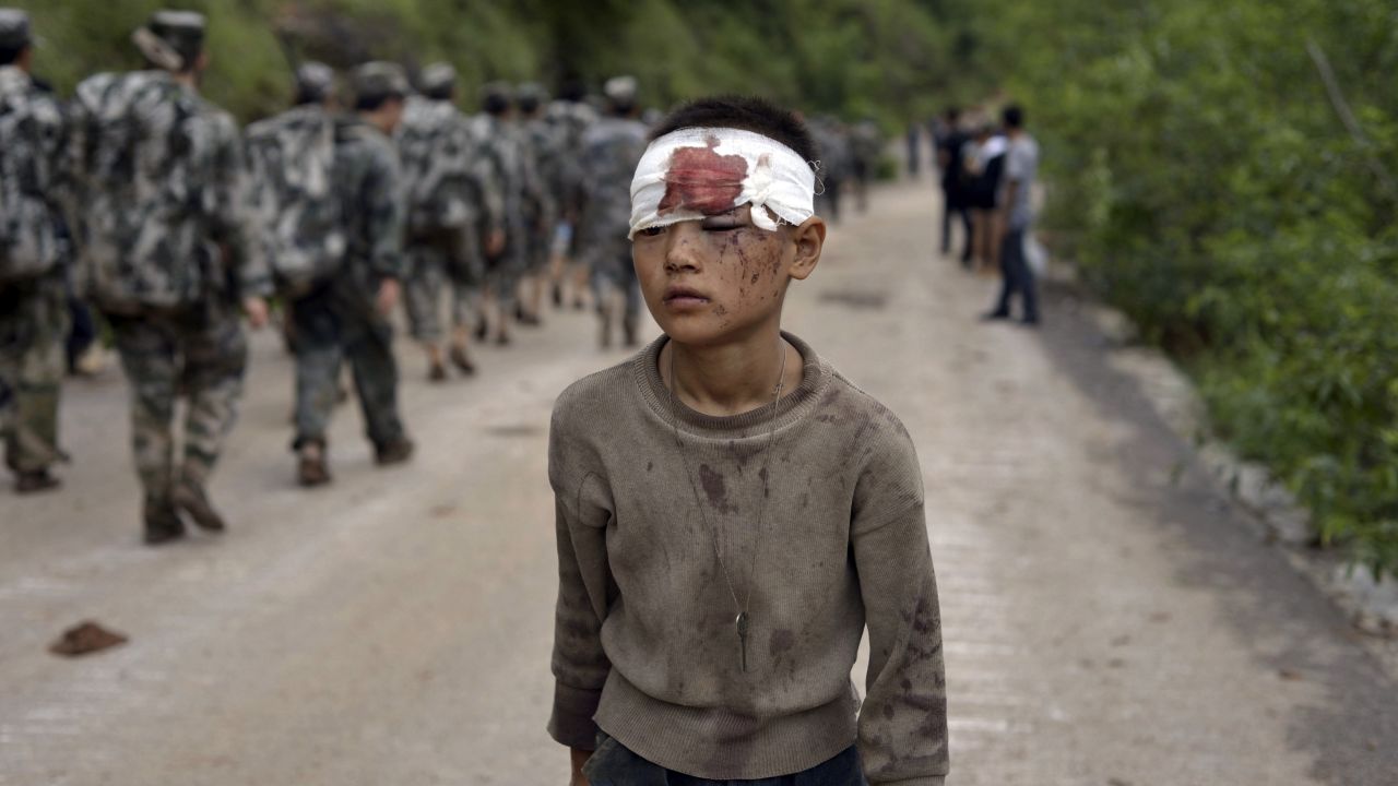 An injured child walks past rescuers heading toward the earthquake's epicenter on August 4.