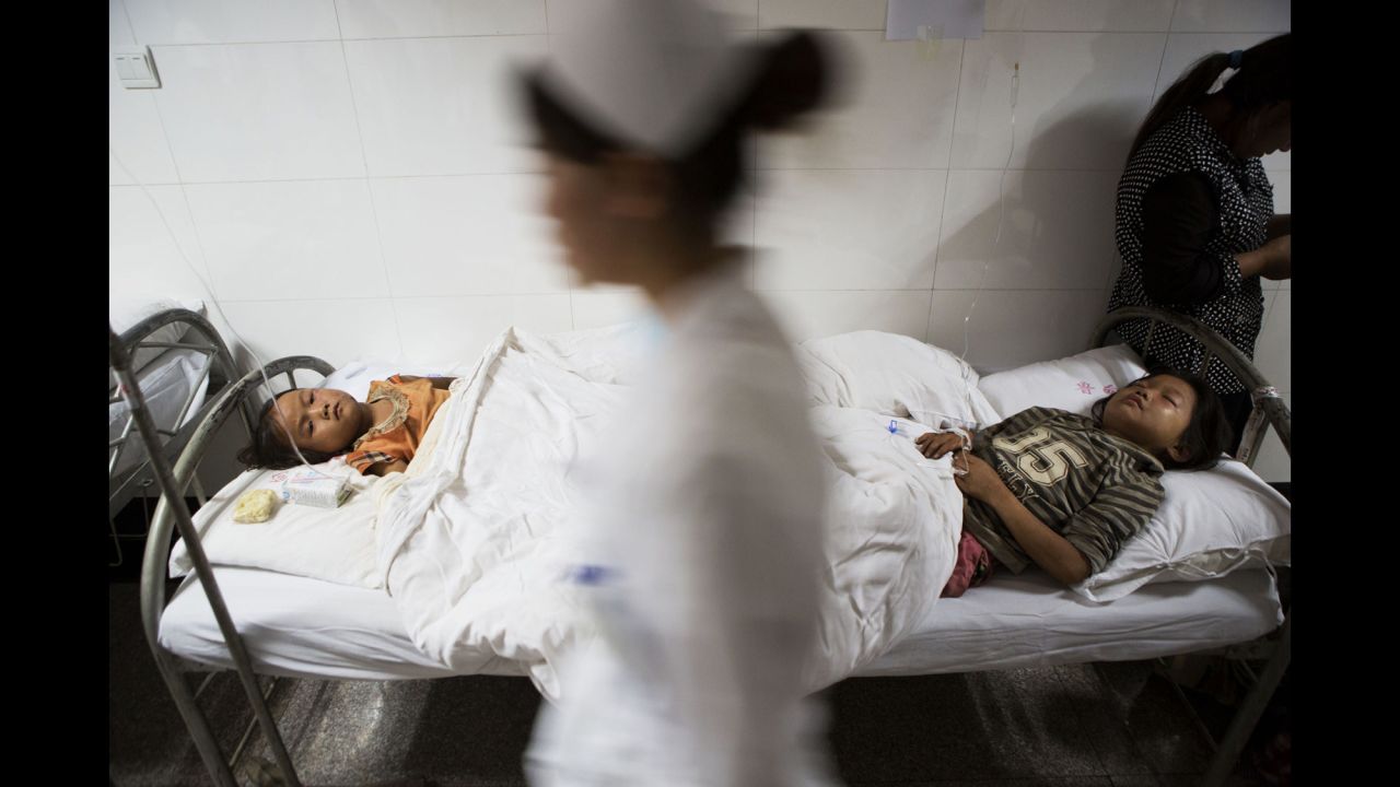 A nurse walks past two injured children at a hospital in Zhaotong on Sunday, August 3.