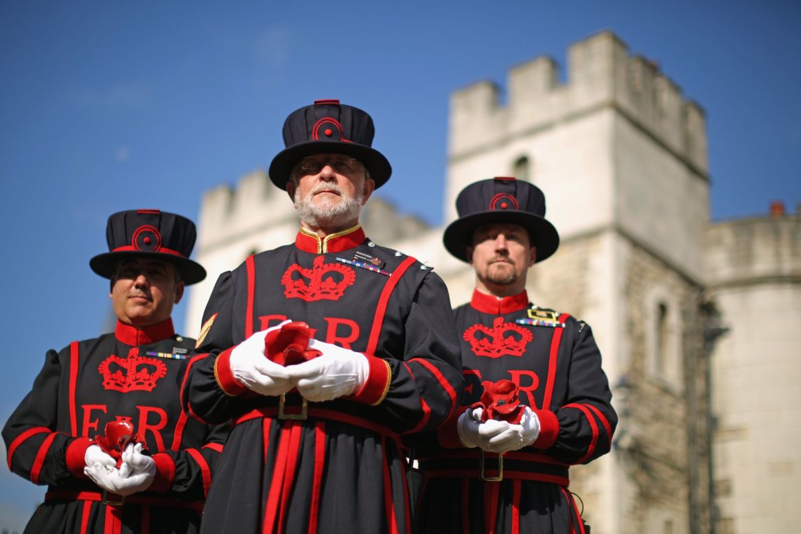 Crawford Butler, center, the longest serving Yeoman Warder at the Tower of London, poses here with the first poppy to be planted at the installation. Work on the project began on July 17, 2014.