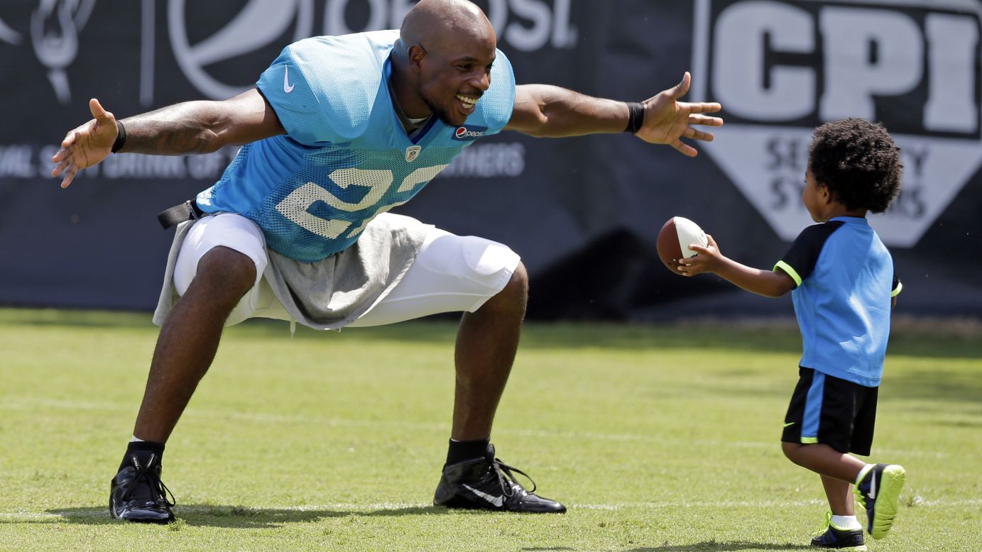 Josh Thomas of the NFL's Carolina Panthers reaches out to hug his son, Dallas, after a practice Tuesday, July 29, in Spartanburg, South Carolina.