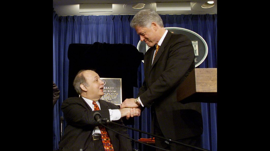 Clinton congratulates Brady in February 2000, when the White House press briefing room was named in his honor.
