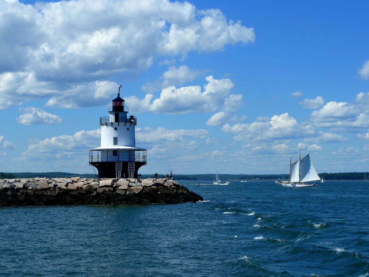 This lighthouse is smaller than most, and it captured <a href="http://ireport.cnn.com/docs/DOC-1157099">Mary Umbricht's</a> attention while visiting Portland, Maine. She is proud of the results: "It was the combination of the clouds, blue sky, the sailboat and how they all came together that I liked about this photo."