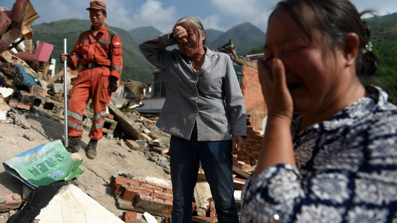 Women react as the body of a relative is found in the collapsed rubble of a home in Longtoushan on August 5.