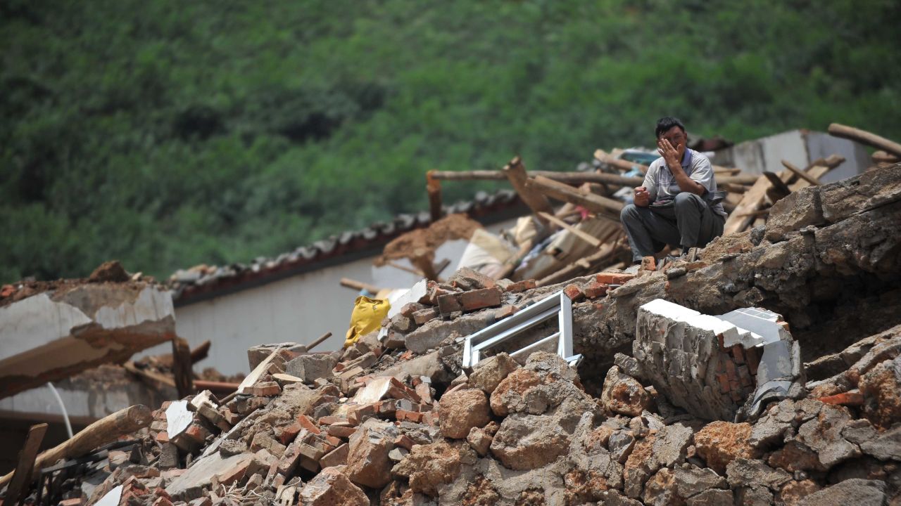 A man sits on the rubble of a collapsed house in Longtoushan on August 5.