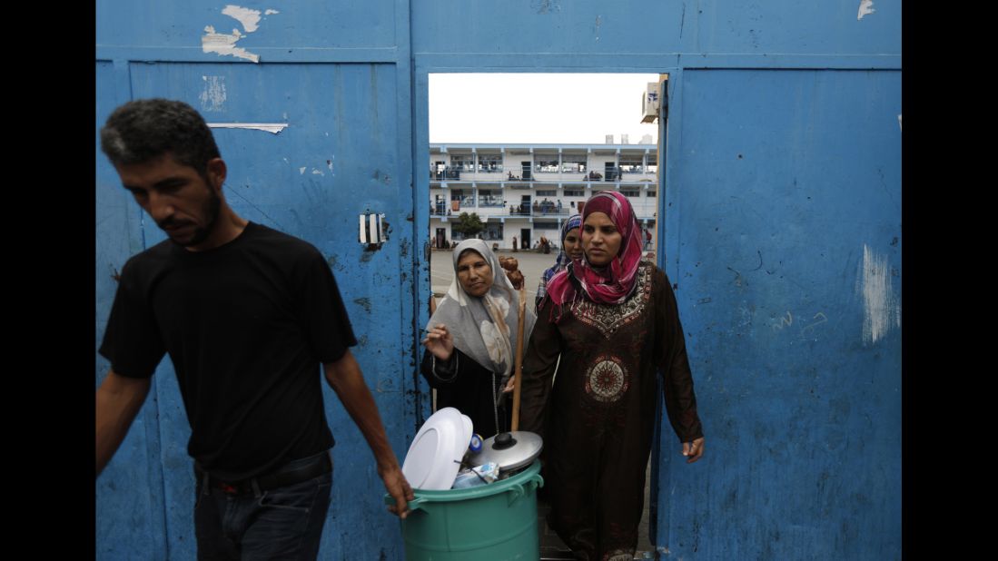 Displaced Palestinians carry their belongings as they leave a United Nations school in Beit Lahiya, Gaza, to return to their homes Tuesday, August 5.