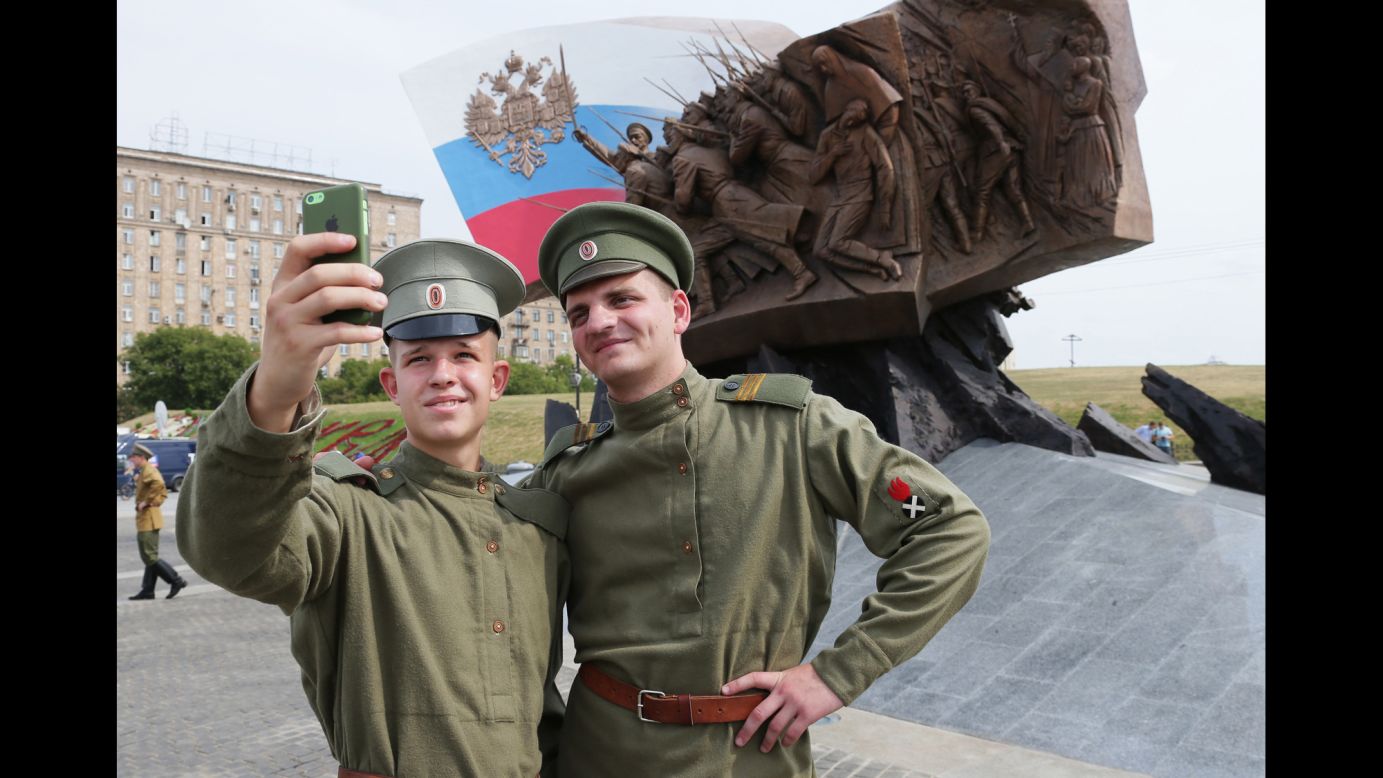 Two Russian soldiers pose in front of a new World War I memorial in Moscow on Saturday, August 2.