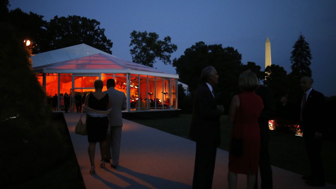 Guests gather outside a tent before dinner. 