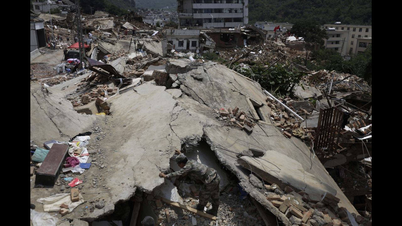 A military rescue worker searches for missing people in the rubble of destroyed houses in Longtoushan, a township in southwest China's Yunnan province, on Wednesday, August 6. The epicenter of a 6.1-magnitude earthquake was recorded in Longtoushan on Sunday, August 3. Hundreds of people have died since, state-run media reported.