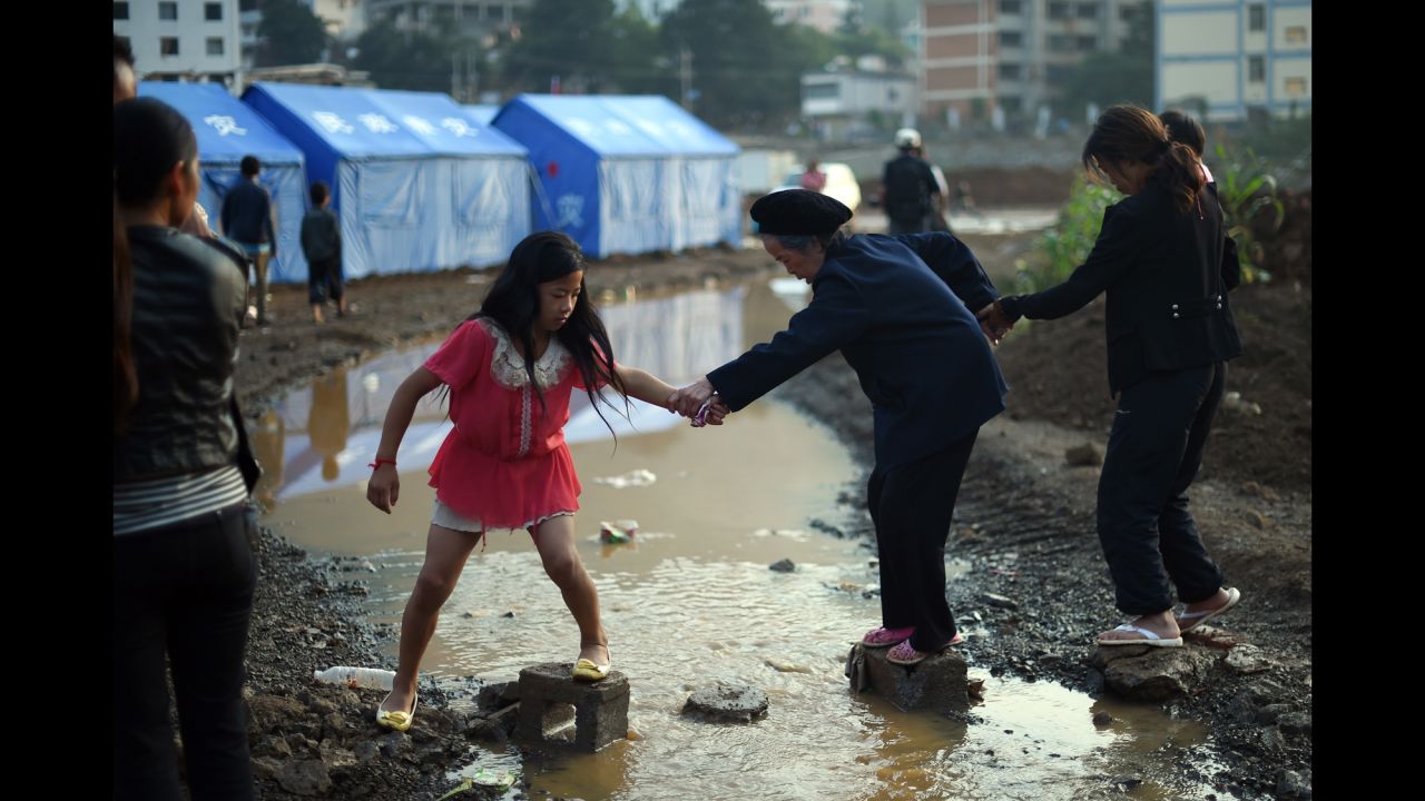 An elderly woman gets help crossing a small creek near tents set up for earthquake survivors in Longtoushan on August 6.