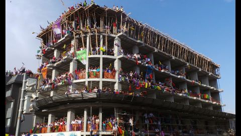 People listen to presidential candidate Selahattin Demirtas, a member of Turkey's main pro-Kurdish party, from an unfinished building as he addresses his supporters in Van, Turkey, on Tuesday, August 5.