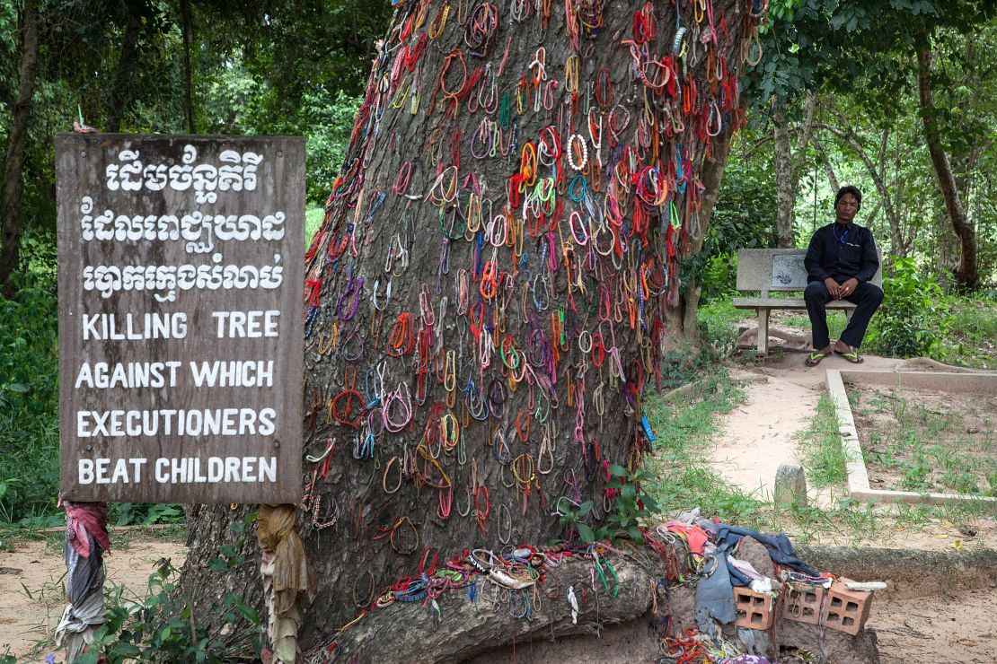 A Cambodian man sits in Choeung Ek Killing Fields near a tree that was used to beat children to death under the Khmer Rouge regime, on August 6, 2014 in Phnom Penh, Cambodia. 