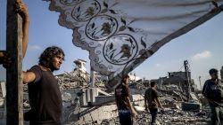 Palestinians stand next to a makeshift shelter erected outside their destroyed house in the devastated neighbourhood of Shejaiya in Gaza City on August 6, 2014.