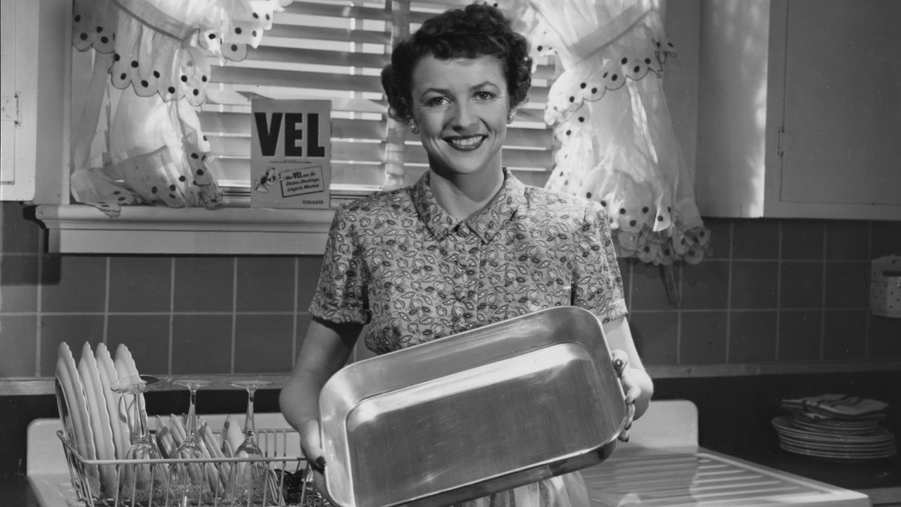 A 1960s housewife shows off her gleaming dishes.
