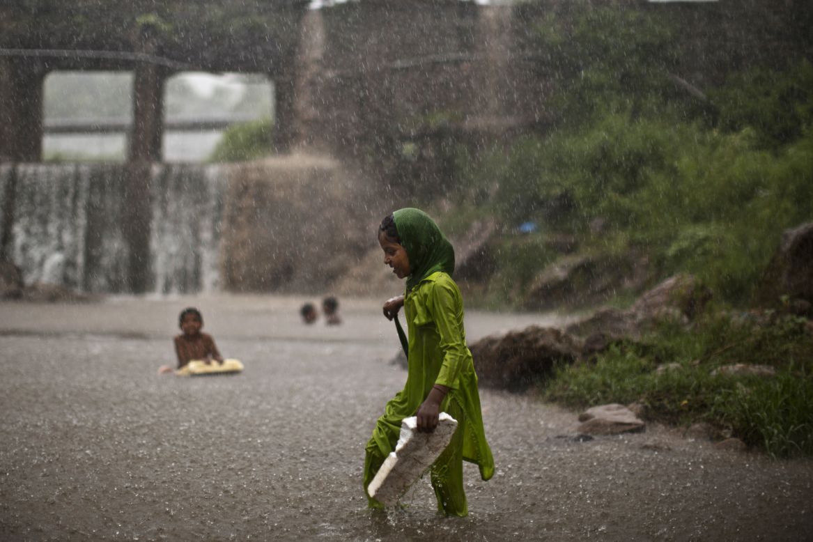 AUGUST 7 - ISLAMABAD, PAKISTAN: A young girl, wades through water looking for shelter from a sudden heavy rainfall after days of scorching temperatures due to a heat wave.