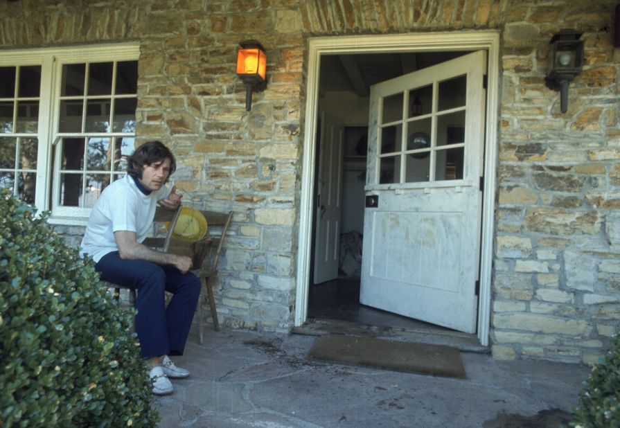 Polanski, who was out of town at the time of the murders, is seen on the porch outside his home. The remnants of the word "pig" can be seen where it was scrawled on the door. 