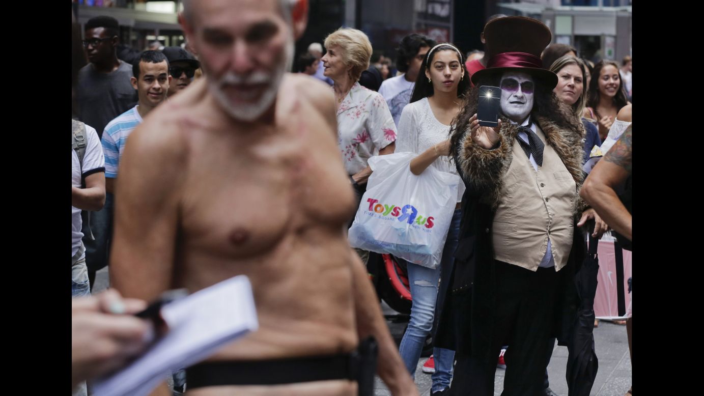 An entertainer dressed as the comic book character Penguin takes a photo of George Davis, who walked through New York's Times Square in the nude after giving a speech Wednesday, August 6. Davis, a candidate for the San Francisco Board of Supervisors, was speaking out against a public nudity ban in San Francisco that was introduced by his opponent, Scott Wiener.