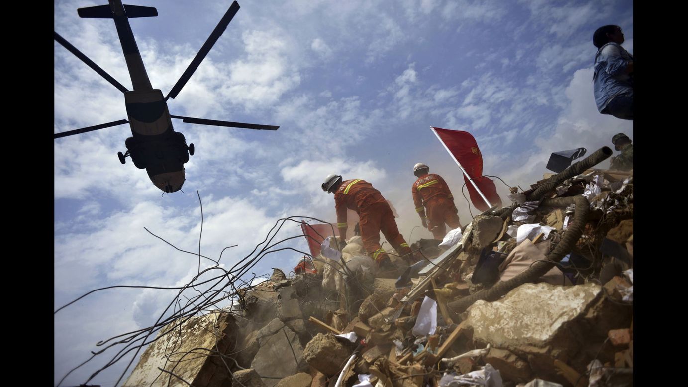 A helicopter flies over rescue workers Monday, August 4, in Longtoushan, China, where the epicenter of a <a href="http://www.cnn.com/2014/08/03/asia/gallery/china-yunnan-earthquake/index.html">6.1-magnitude earthquake</a> was recorded a day earlier. Hundreds of people have died since, state-run media reported.