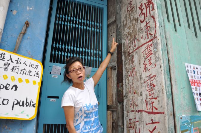 Maria Kwok, a volunteer tour guide who has lived in the neighborhood for almost 30 years, points out old Chinese characters on a wall of the Blue House.