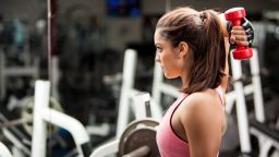 Gorgeous young woman using dumbbells to work on her triceps. 